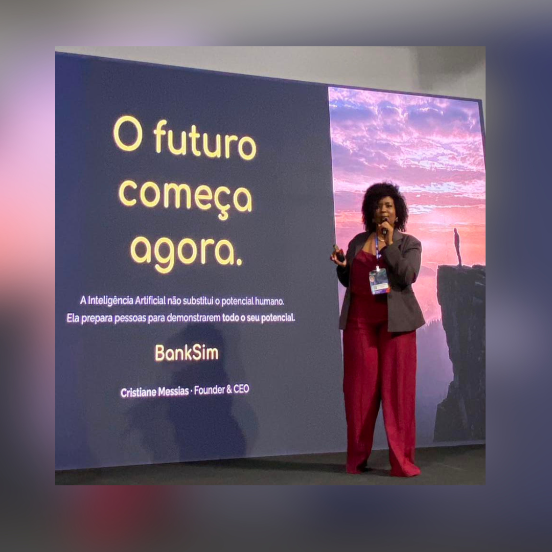 Cristiane Messias, founder e CEO da Lumbre, palestrando no palco com o telão exibindo “O futuro começa agora” e a marca BankSim